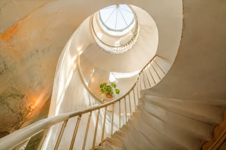Escalier en colimaçon blanc éclairé par une verrière, image du chemin malgré le doute